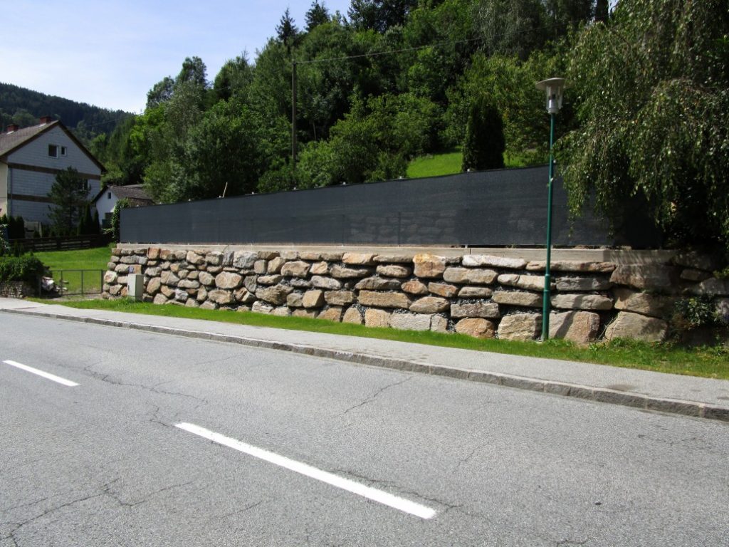 Stützmauer aus großen Natursteinen entlang einer Straße